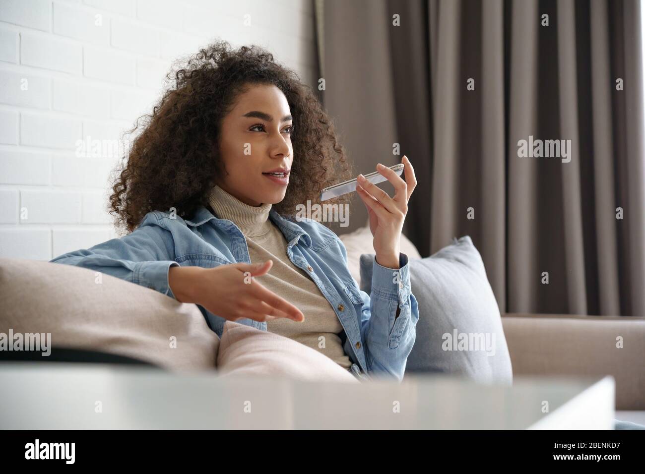 Ragazza africana che utilizza assistente vocale digitale virtuale sull'app per telefono cellulare. Foto Stock