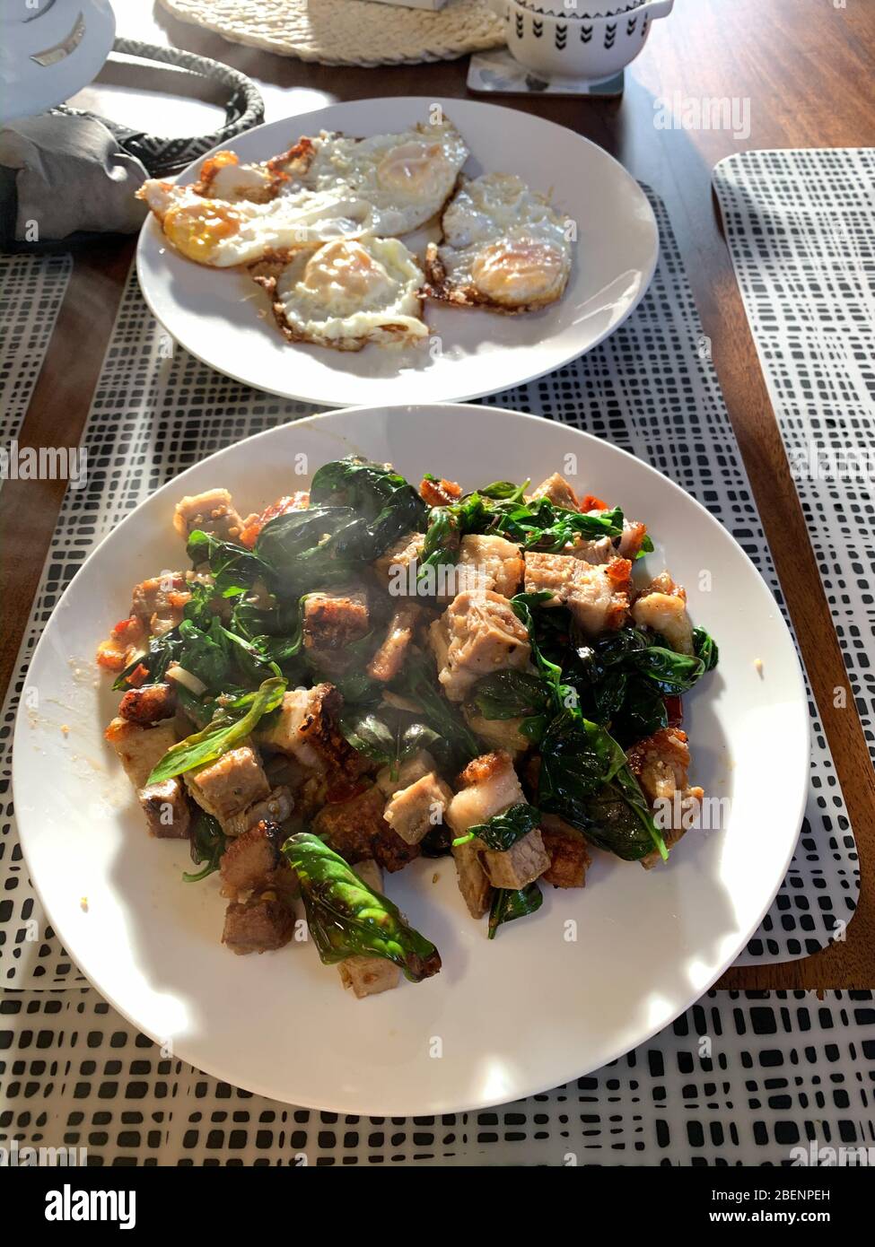 Croccante basilico di maiale alla pancia cotta con uova cotte in stile thailandese su piatti bianchi. Foto Stock