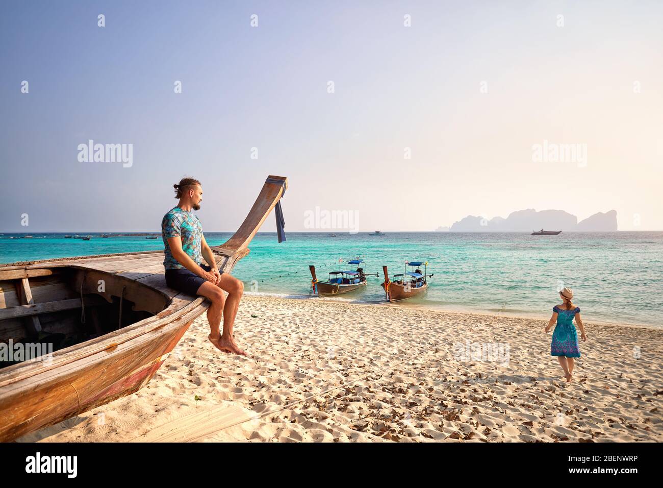 L'uomo sulla barca dalla coda lunga e le donne a piedi al mare sulla spiaggia tropicale di Phi Phi island nel sud della Thailandia. Travel Magazine Concept. Foto Stock