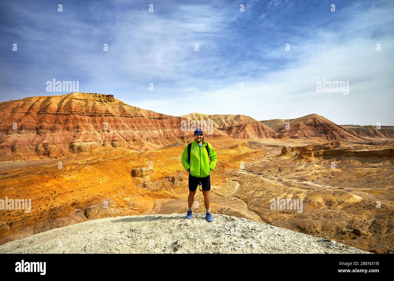 Turisti in giacca verde con surreale di rosso e di giallo in montagna in background nel parco deserto Altyn Emel in Kazakistan Foto Stock