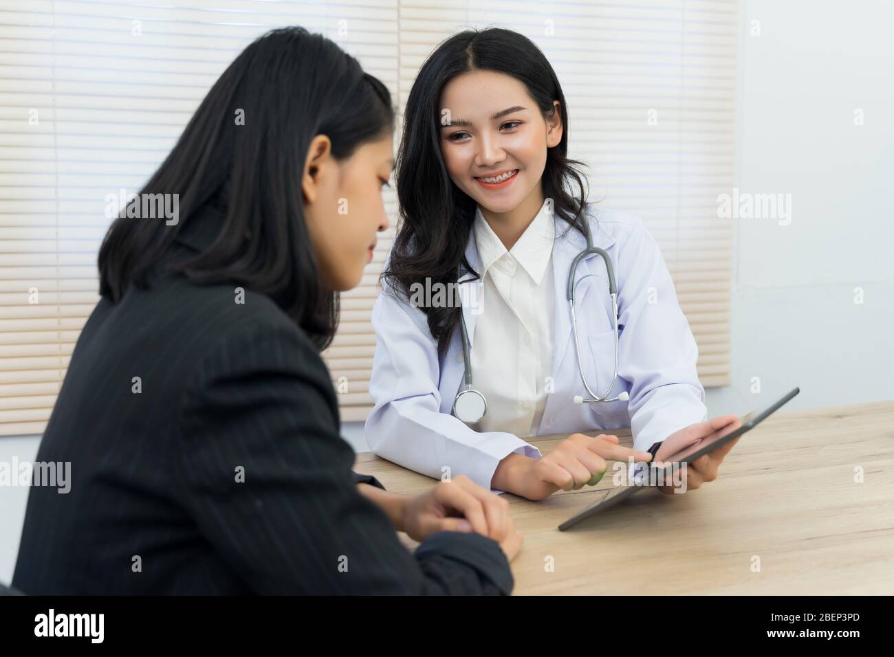 La giovane medico asiatica fa consultazione e ascolta i sintomi della paziente adulta femminile in ufficio. Paziente che ha consultato il medico in offic Foto Stock