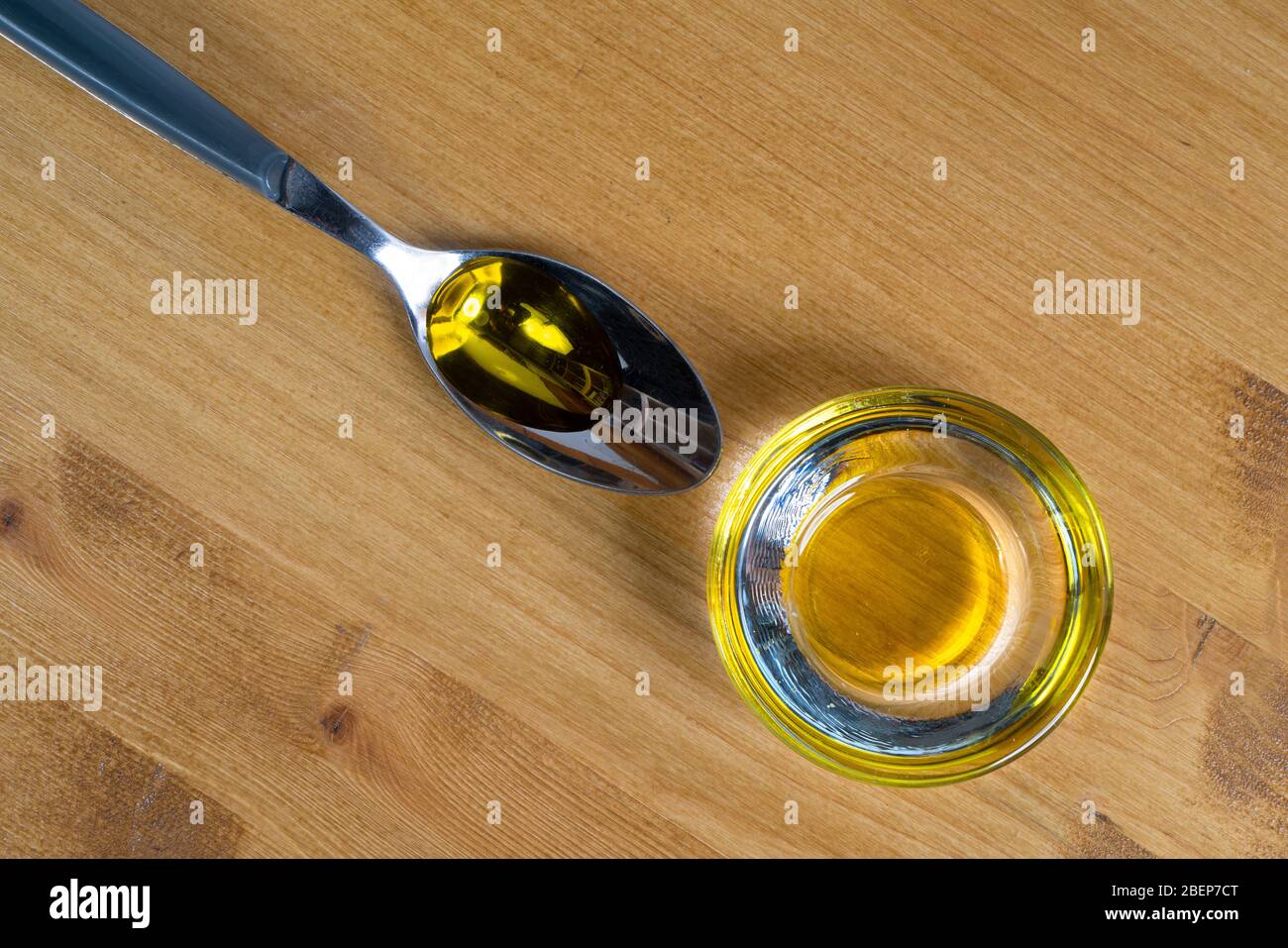 un cucchiaio e un contenitore di vetro con olio d'oliva Foto Stock