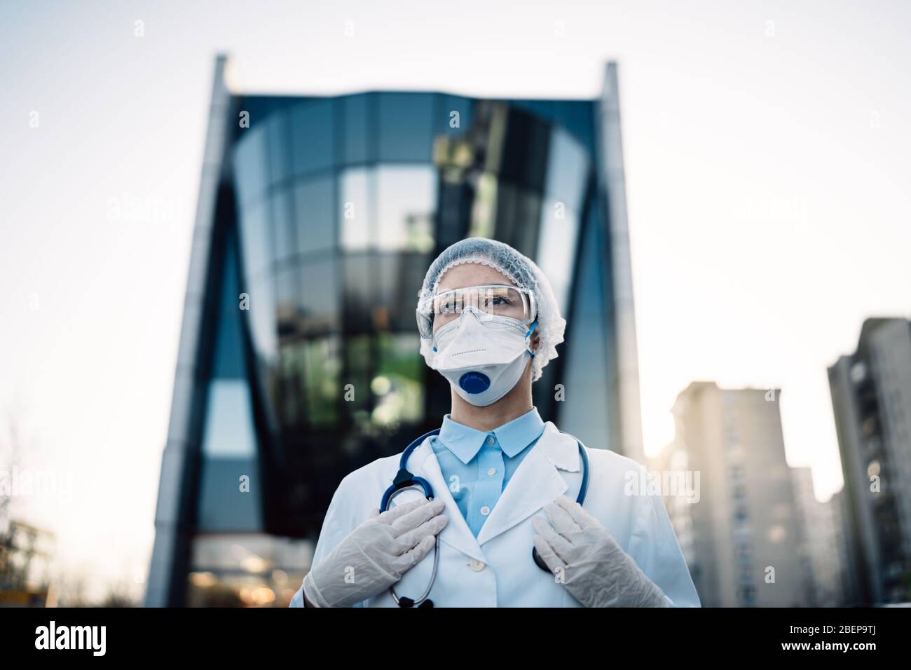 Medico di coronavirus in piedi di fronte alla costruzione moderna clinica, lavorando nell'isolamento Ward.Medical professionale in dispositivi di protezione nella lotta aga Foto Stock