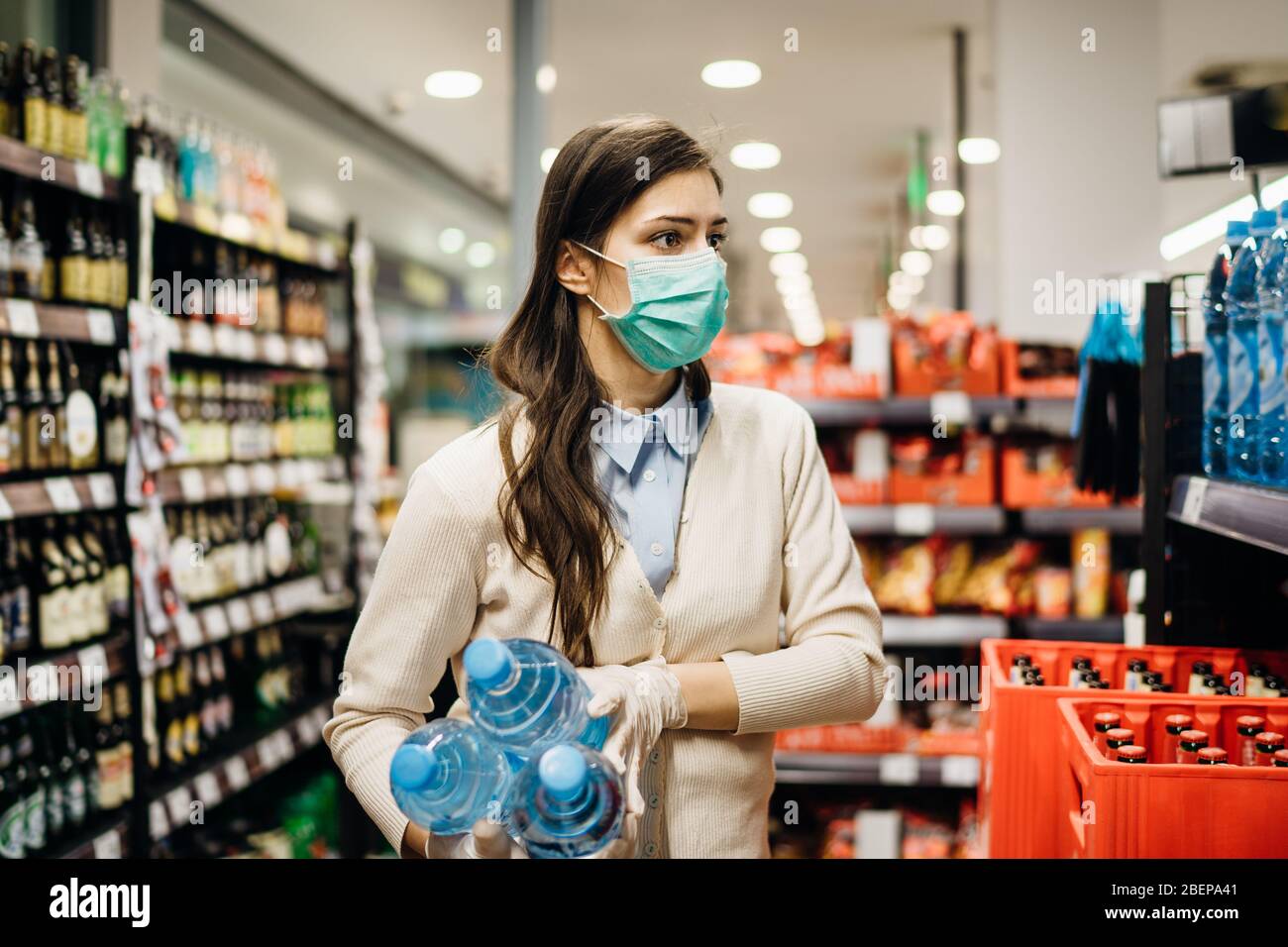 Donna con maschera sicuro shopping per generi alimentari in mezzo al coronavirus pandemic in un rifornito negozio di alimentari.COVID-19 cibo di acquisto in supermercato.Panic buyin Foto Stock