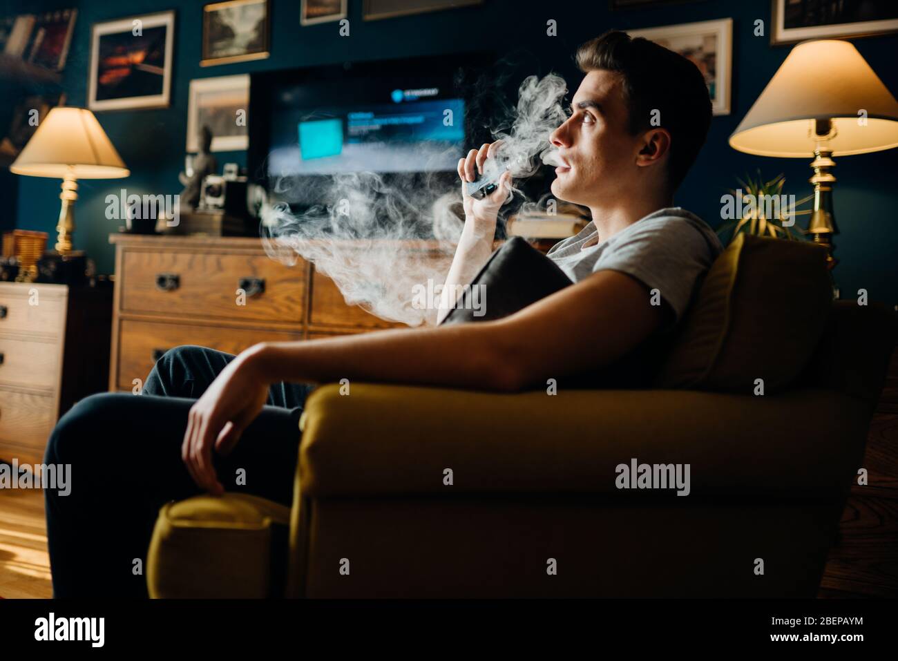 Uso del genitore di e-sigarette nel home.Young uomo che inala di un vapore con sigaretta elettronica.Vape sapore liquido chemicals.Smoking e vaporing negativ Foto Stock