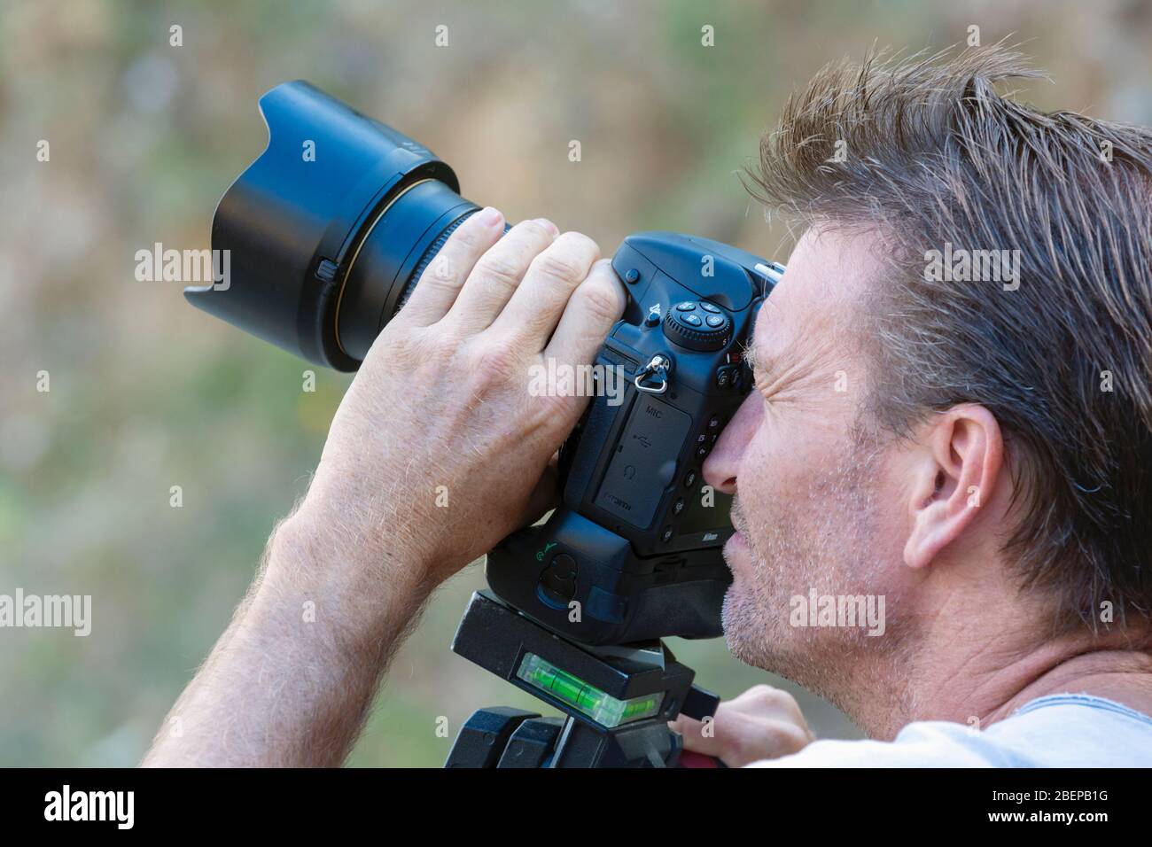 Fotografo che lavora con una fotocamera DSLR. Utilizza una Nikon D800 con obiettivo Nikkor 24 mm F2.8 stabilizzato su una testa a treppiede Mandotto. Foto Stock