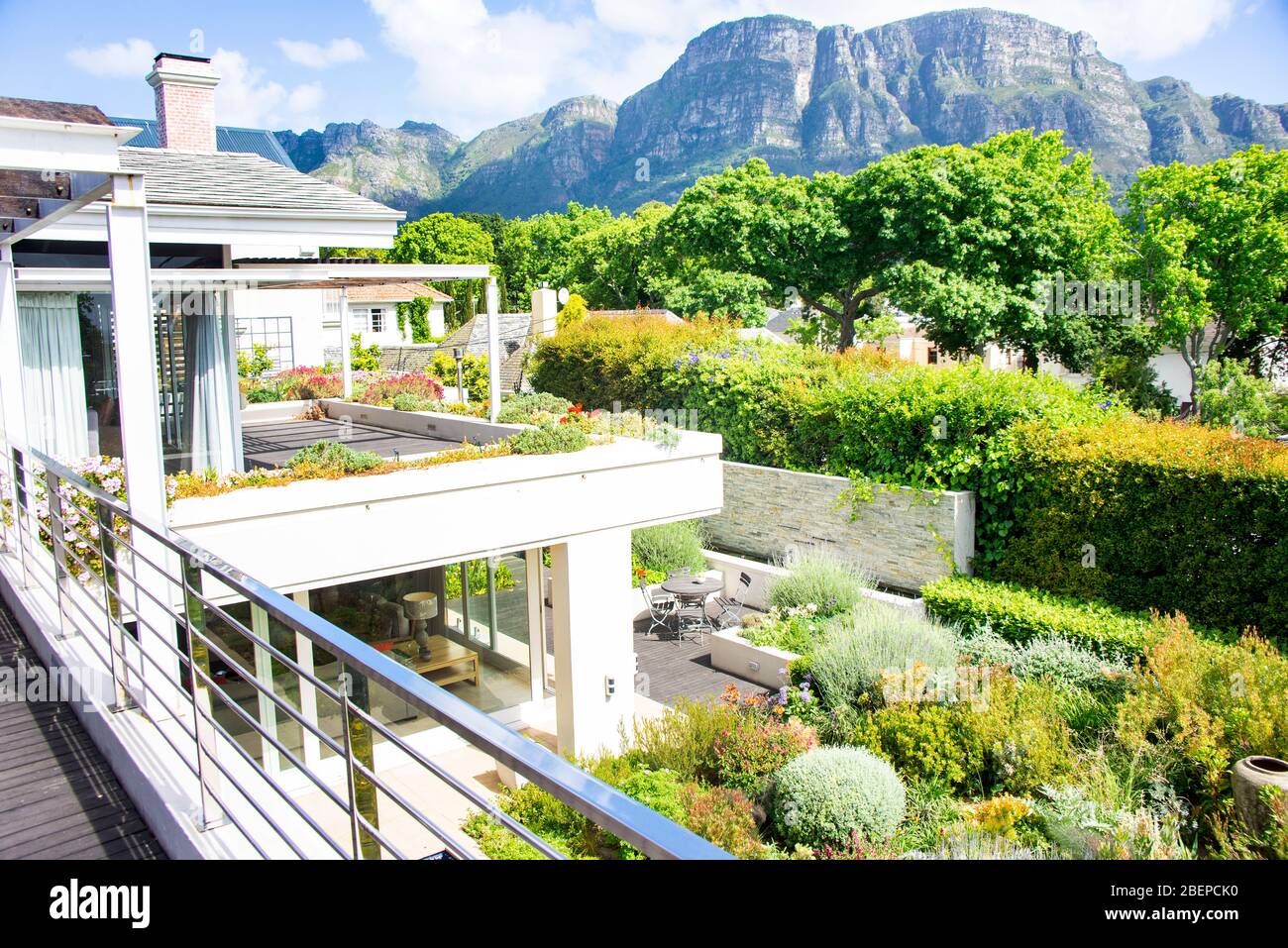 Una grande casa si trova a Claremont, un frondoso ed esclusivo sobborgo di Città del Capo. La casa moderna è tipica dei palazzi trovati in Sud Africa. Un bellissimo giardino di piante indigene si trova sotto. La rabbia di Table Mountain si trova sullo sfondo. Anche se il quartiere ha principalmente residenti bianchi, un sacco di occupazione è creato per costruire e mantenere le proprietà e le strade. Foto Stock