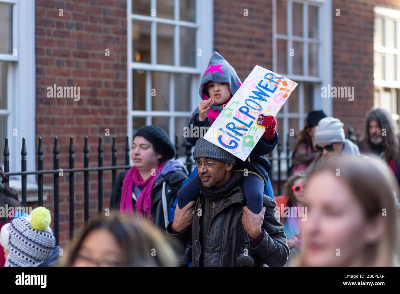 Giovane ragazza seduta sulle spalle di un uomo tenendo un cartello con scritto 'Girl Power', alla marcia delle Donne del 2017, Londra Foto Stock