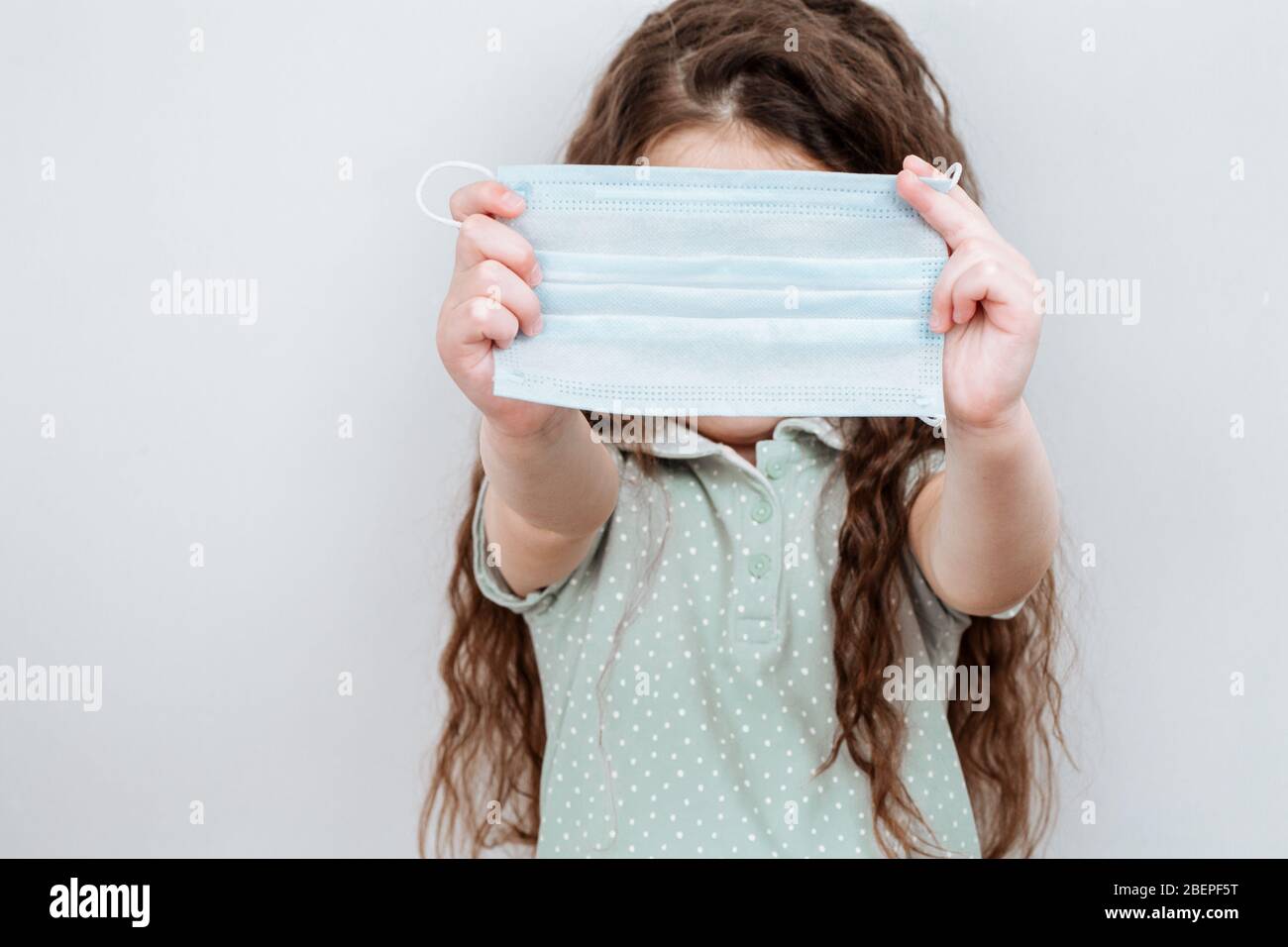 Una ragazza tiene una maschera medica nelle sue mani. Prevenzione delle infezioni e diffusione del coronavirus, quarantena. Foto Stock