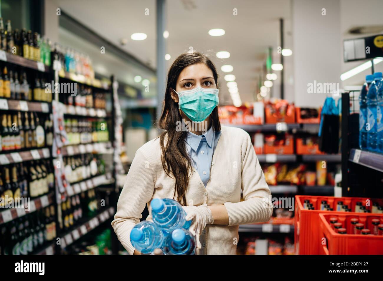 Donna con maschera sicuro shopping per generi alimentari in mezzo al coronavirus pandemic in un rifornito negozio di alimentari.COVID-19 cibo di acquisto in supermercato.Panic buyin Foto Stock