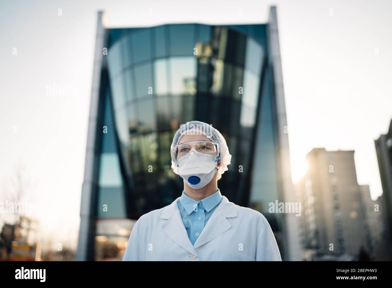 Medico di coronavirus in piedi di fronte alla costruzione moderna clinica, lavorando nell'isolamento Ward.Medical professionale in dispositivi di protezione nella lotta aga Foto Stock