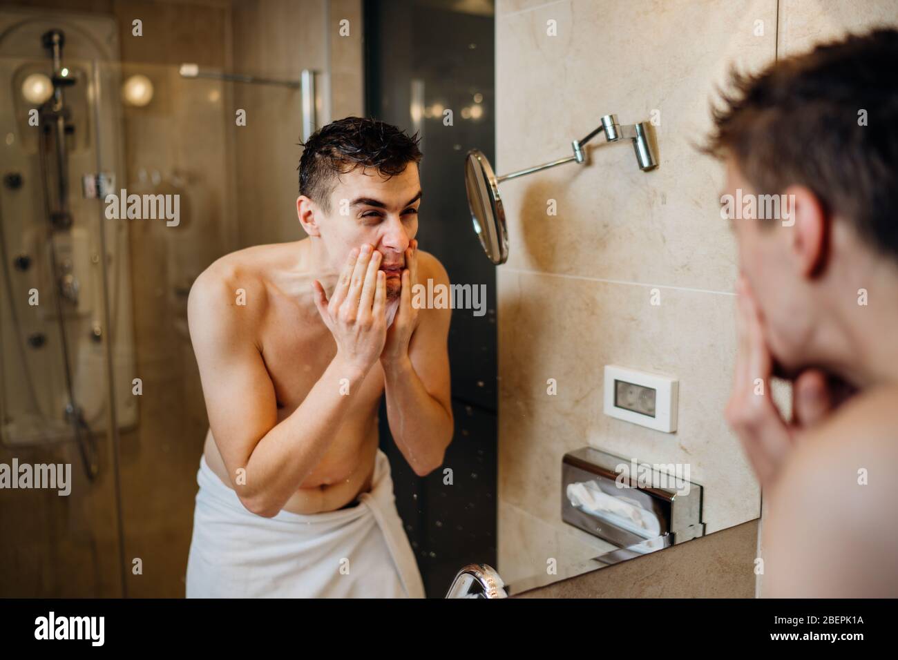 Giovane uomo che ha una procedura quotidiana di rasatura della barba, applicando lozione di aftershave.eruzione cutanea allergica pruriginosa reazione alla cura della pelle igiene product.Faci Foto Stock