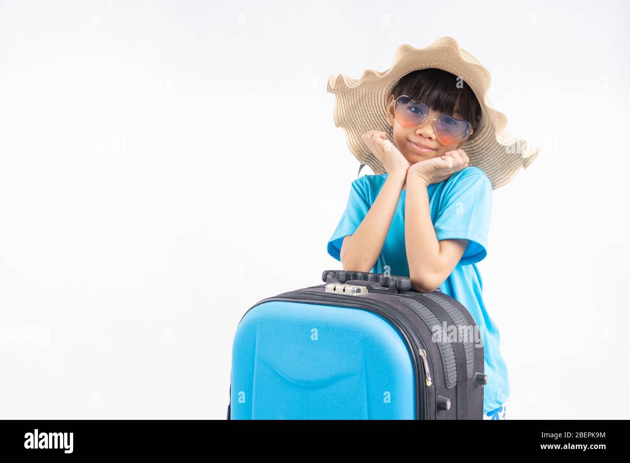 Ritratto di giovane asiatico con borsa da viaggio, ragazza tailandese indossare in stile estivo in camicia blu che si prepara a mare contro parete bianca in studio Foto Stock