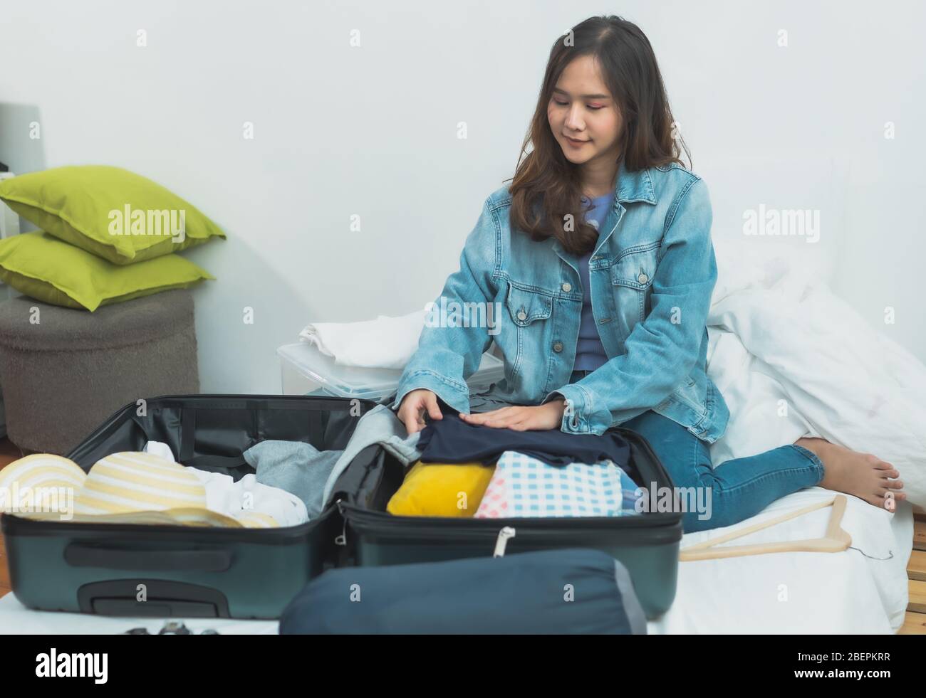 Preparazione e pianificazione del viaggio sul concetto di vacanza, tailandese e Asia donna felice che imballano i vestiti in valigia bagaglio borsa per viaggiare a letto Foto Stock