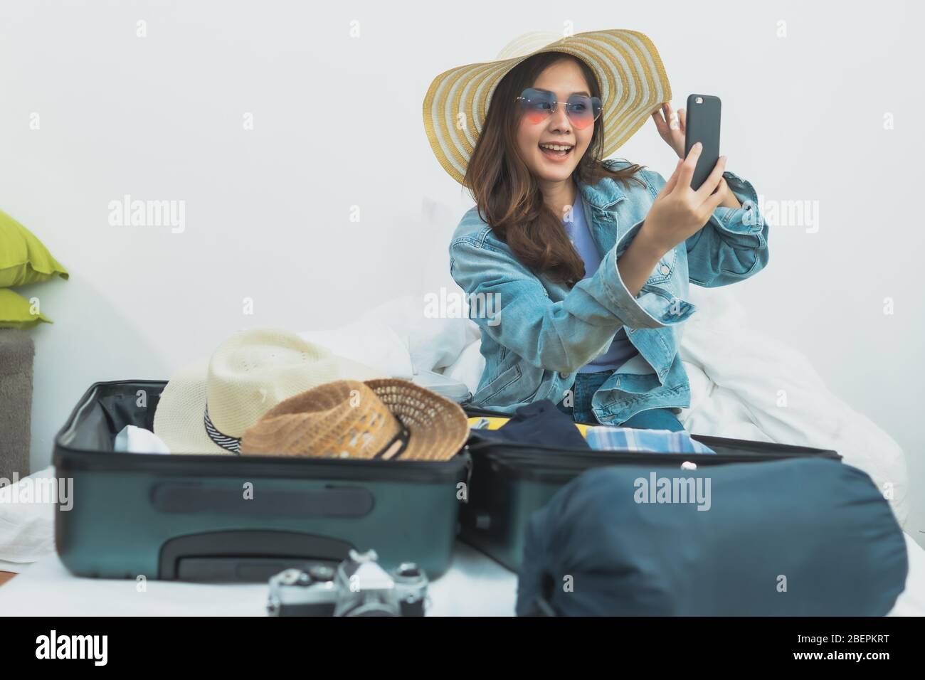 Preparazione e pianificazione del viaggio sul concetto di vacanza, tailandese e Asia donna felice provare su vestiti e accessori e tack una foto prima di imballaggio in lug Foto Stock