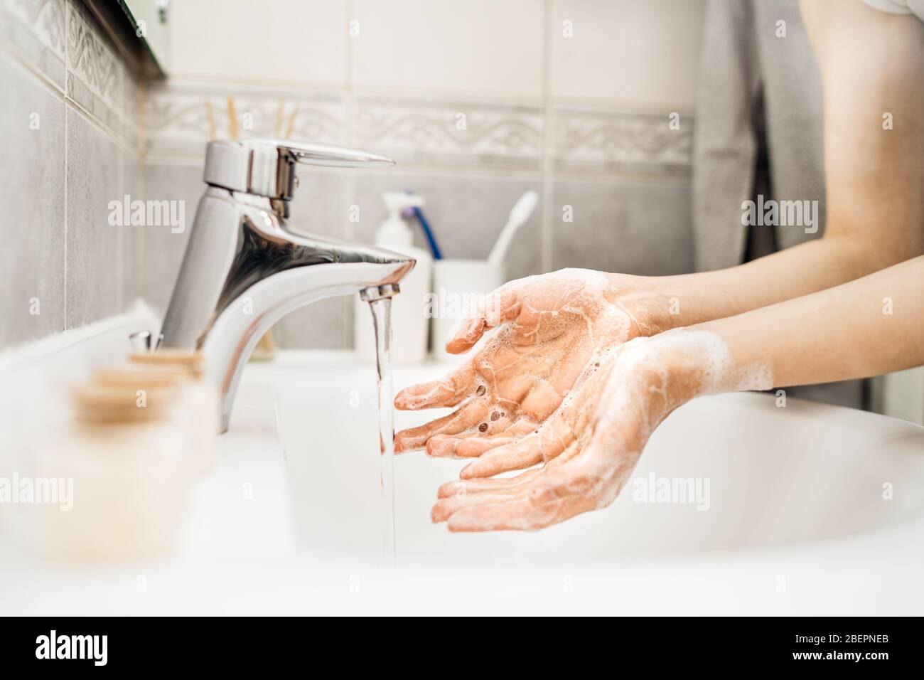 Donna lavando le mani con acqua e sapone in un bagno pulito.protocollo di decontaminazione, igiene delle mani routine. Pulizia delle mani regolarmente. Malattia infettiva Foto Stock