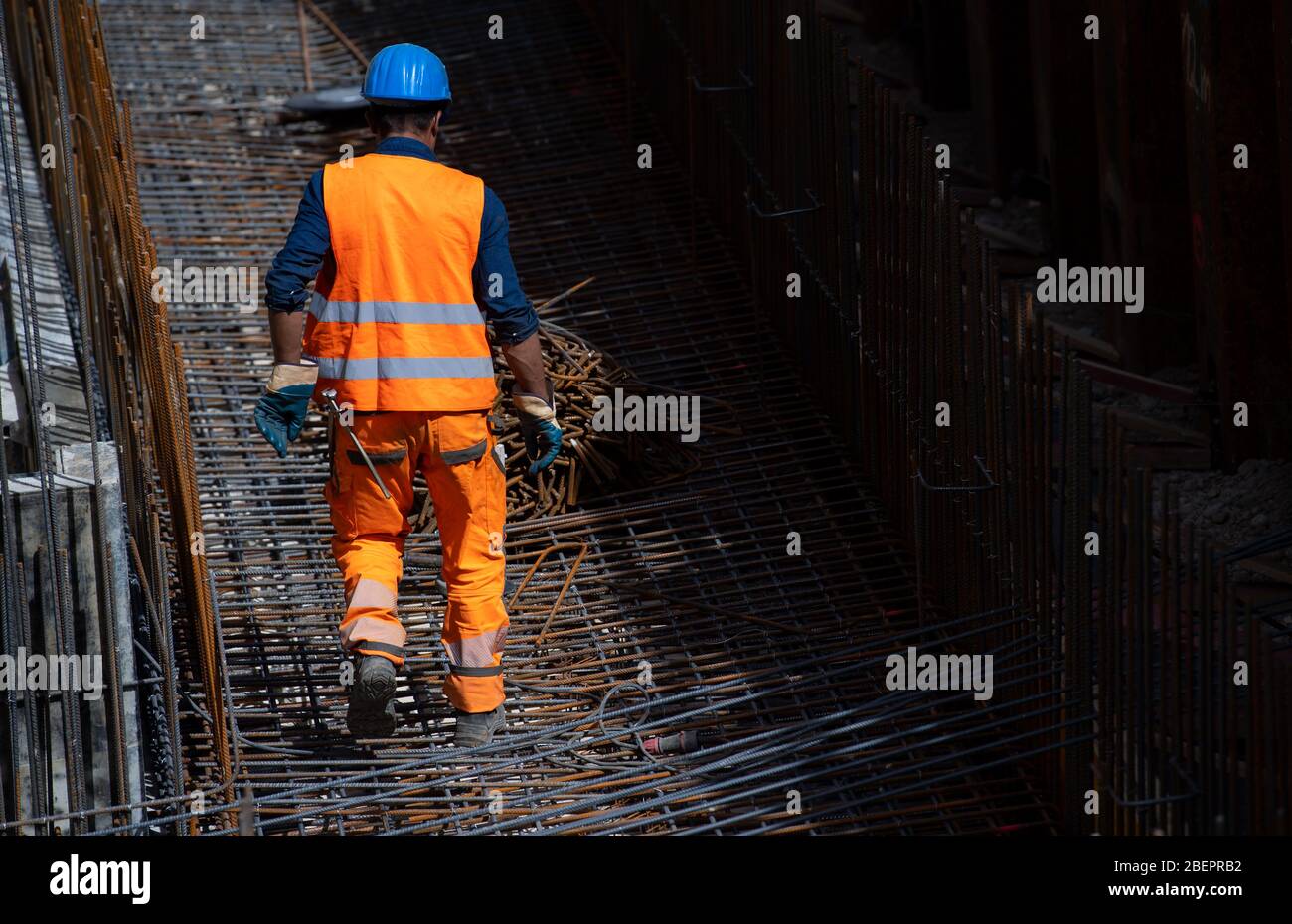 Monaco, Germania. 15 aprile 2020. Un lavoratore edile depone dei tappetini in acciaio sul cantiere del nuovo centro di giustizia penale. Dopo il suo completamento, il nuovo edificio di Leonrodplatz, che copre circa 39,000 metri quadrati, sostituirà l'edificio in invecchiamento di Nymphenburger Strasse. Tra gli altri, parti dei due tribunali regionali, il Tribunale regionale superiore e gli uffici pubblici dei procuratori di Monaco si sposteranno nell'edificio stimato a 300 milioni di euro. Credit: Sven Hoppe/dpa/Alamy Live News Foto Stock