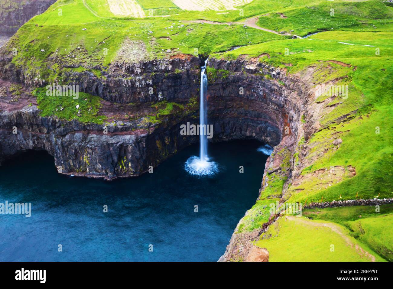 Vista dall'alto della cascata di Mulafossur nel villaggio di Gasadalur, isola di Vagar delle Isole Faroe, Danimarca. Fotografia di paesaggio Foto Stock