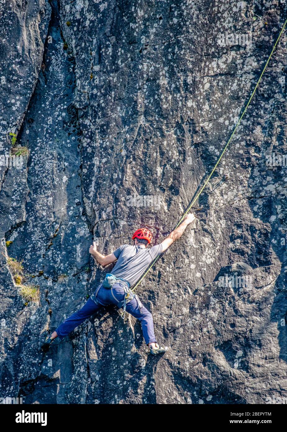 Scalatore esteso su una rockface ardesia in una cava Cumbria Foto Stock