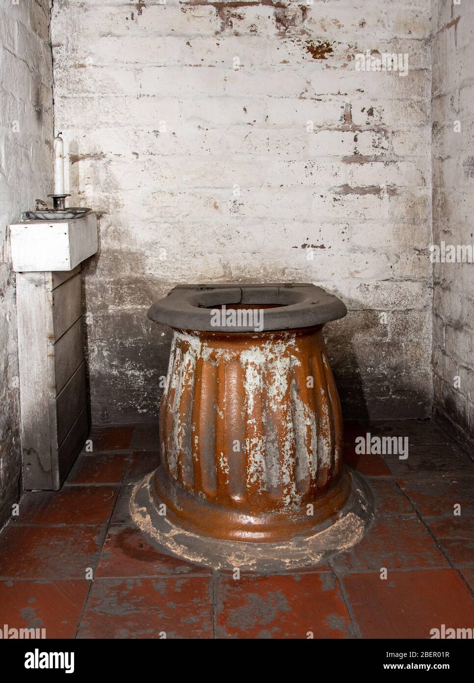 Vecchio bagno esterno nell'edificio esterno con mattoni imbiancati e pavimento in piastrelle di cava Foto Stock