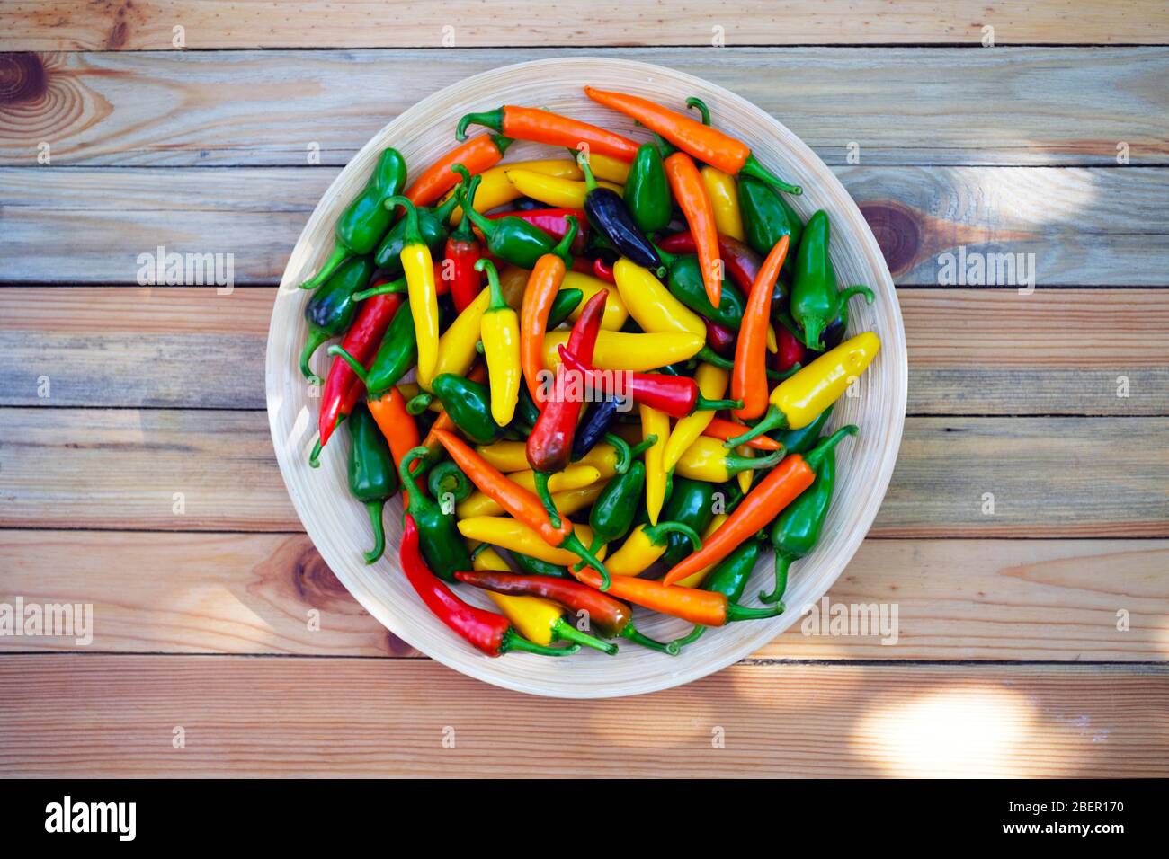 Colori misti peperoni caldi su piano di legno. Fotografia alimentare Foto Stock