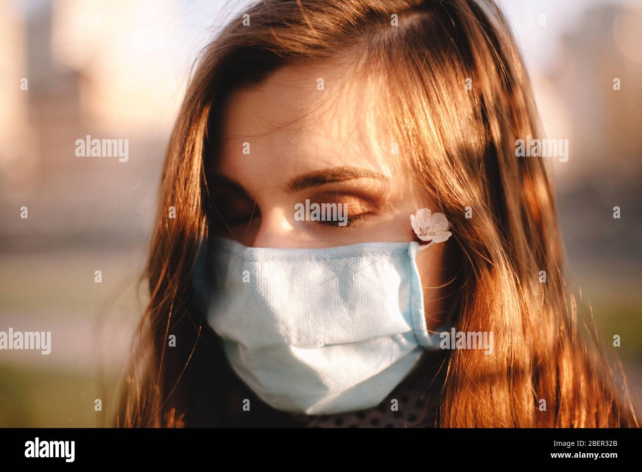 Primo piano ritratto di giovane donna che indossa faccia medica maschera in piedi all'aperto Foto Stock