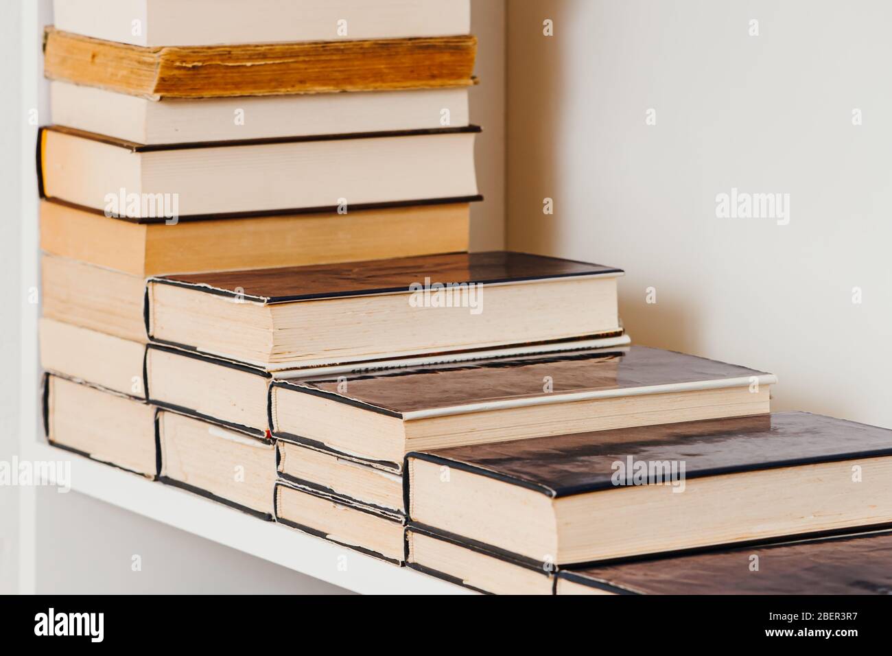 Vecchi libri sulla mensola bianca allineati come scale con copy space concetto Foto Stock