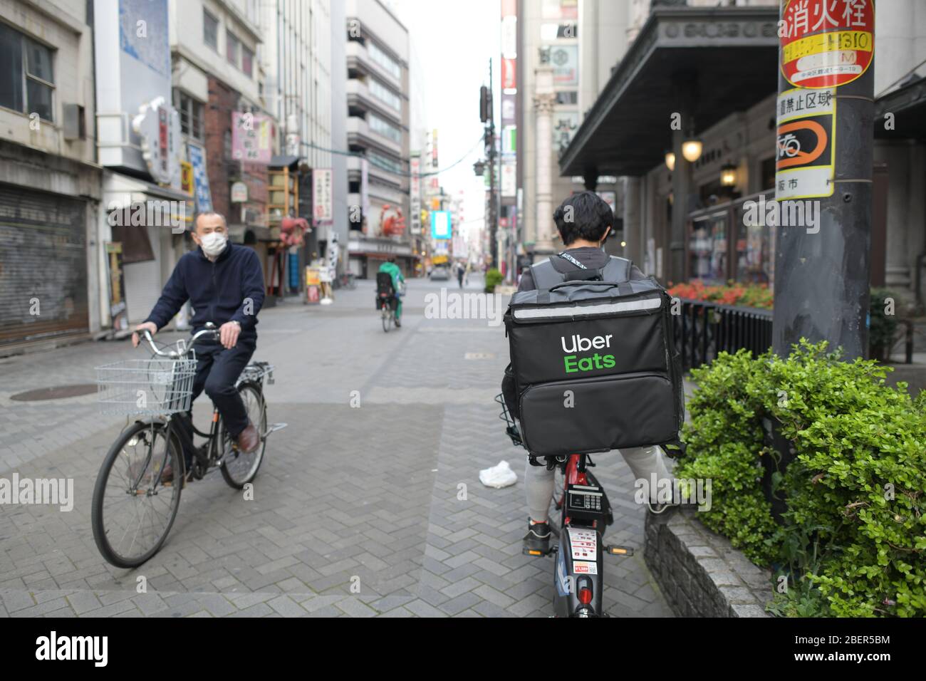 OSAKA, GIAPPONE - APRILE 15: Un uomo di consegna di Uber mangia il suo telefono mobile nel quartiere di intrattenimento della zona di Dotonbori il 15 aprile 2020 a Osaka, Giappone. La scorsa settimana il primo ministro giapponese Shinzo Abe ha dichiarato lo stato di emergenza per Tokyo e per altre sei prefetture, tra cui Osaka, per aumentare le difese contro la diffusione del coronavirus. (Foto: Richard Atrero de Guzman/AFLO) Foto Stock