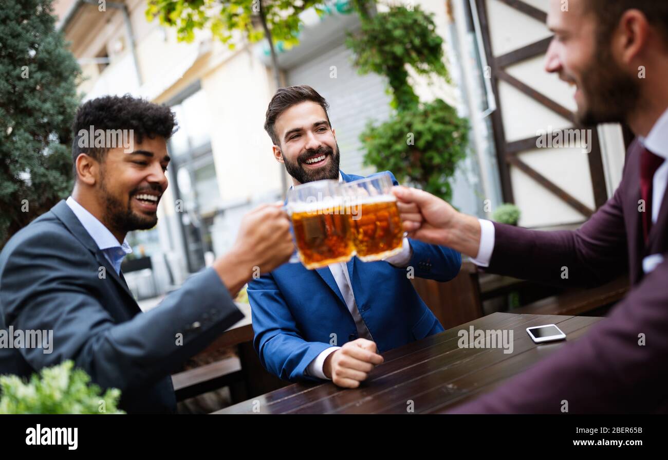 Vecchi amici allegri che si divertono e bevono birra al banco bar nel pub. Foto Stock