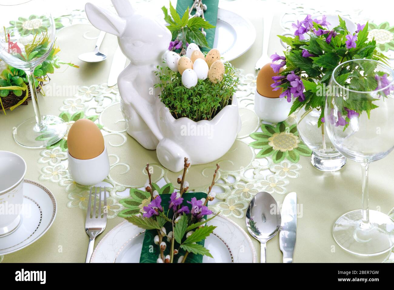Elegante festa di Pasqua arredamento tavolo con freschi primi fiori viola primavera, foglie di cress e uova. Foto Stock