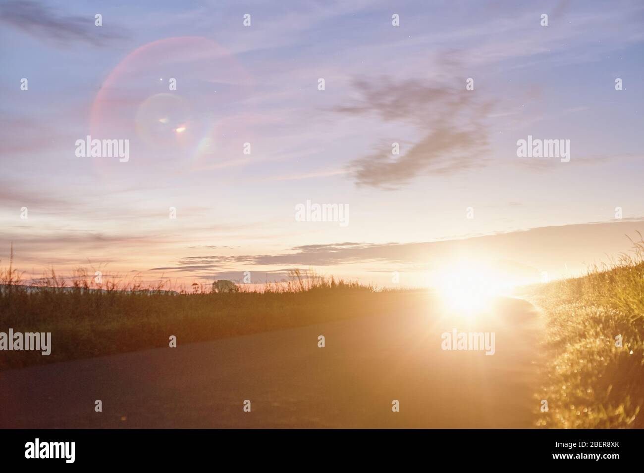 Alba su un campo con un auto in avvicinamento Foto Stock