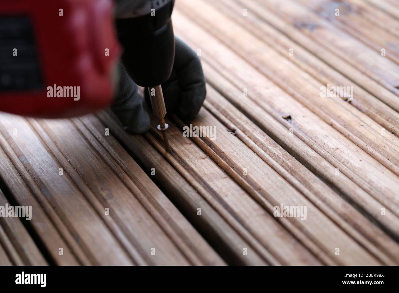 Fai da te costruzione di un portico / balcone pavimento con tavole di legno marrone a Espoo, Finlandia, febbraio, 2020. Persona che usa la macchina di perforazione per costruire il pavimento. Foto Stock