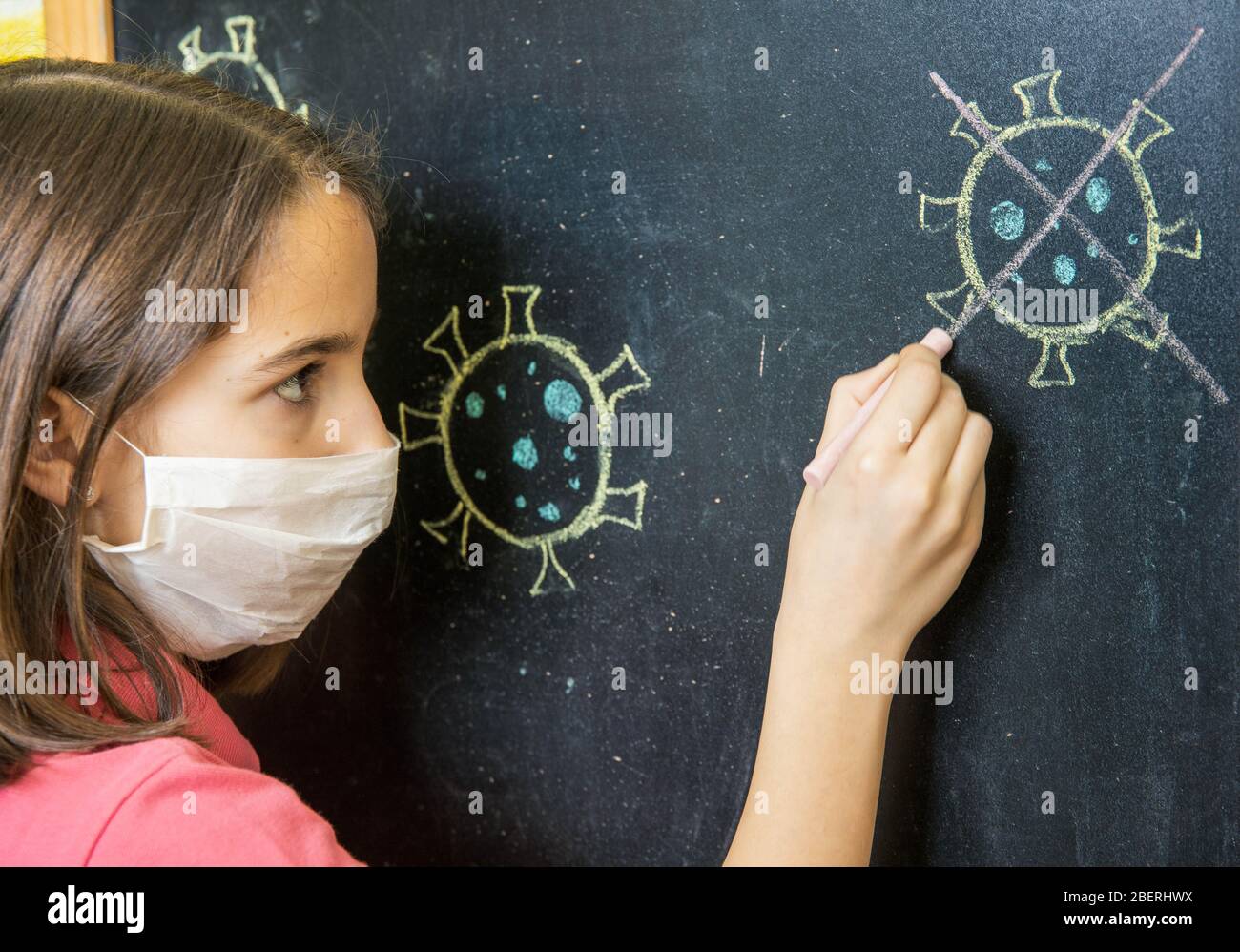 Ragazza triste che attraversa il disegno di un coronavirus su una lavagna Foto Stock