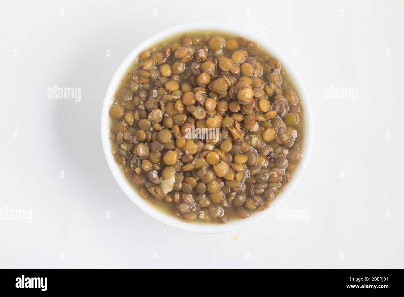 Lenticchie cotte in una ciotola su sfondo bianco Foto Stock