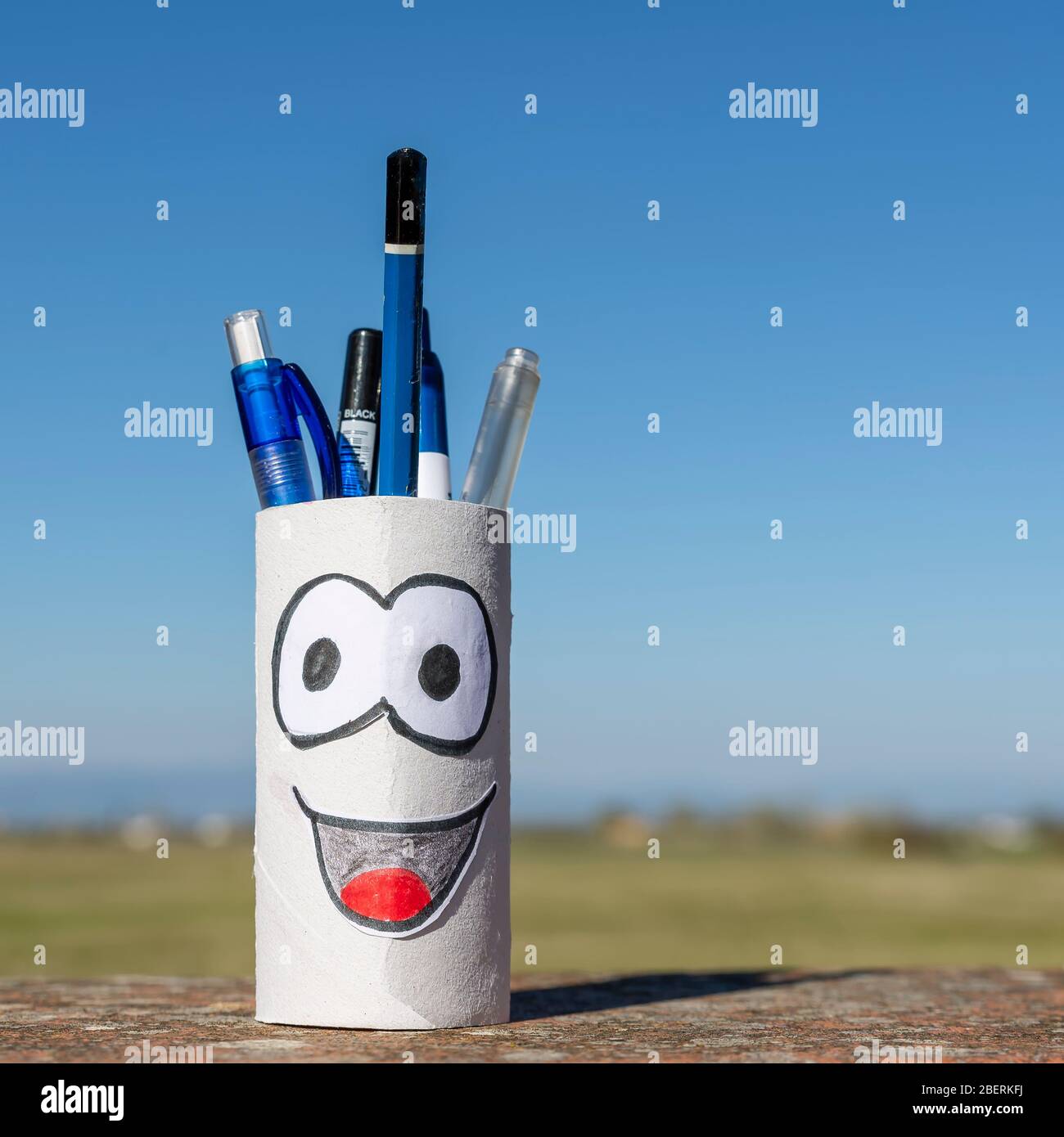 Riutilizzo creativo di un rotolo di carta igienina finito trasformato in un portapenne contro un bellissimo cielo blu Foto Stock