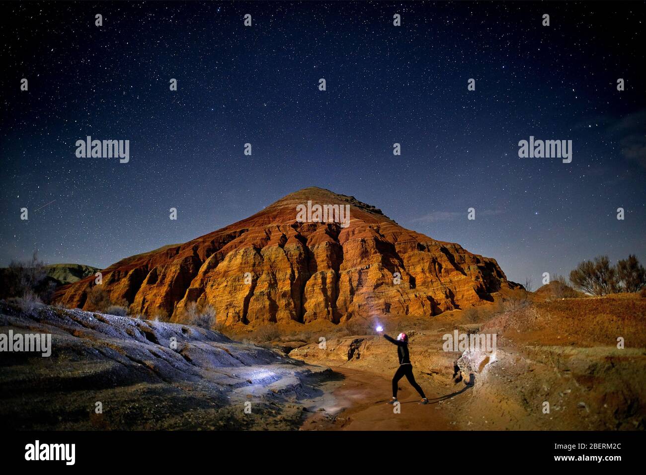 Uomo con testa luce nel deserto di notte sullo sfondo del cielo. Viaggi, avventuri e concetto di spedizione. Foto Stock