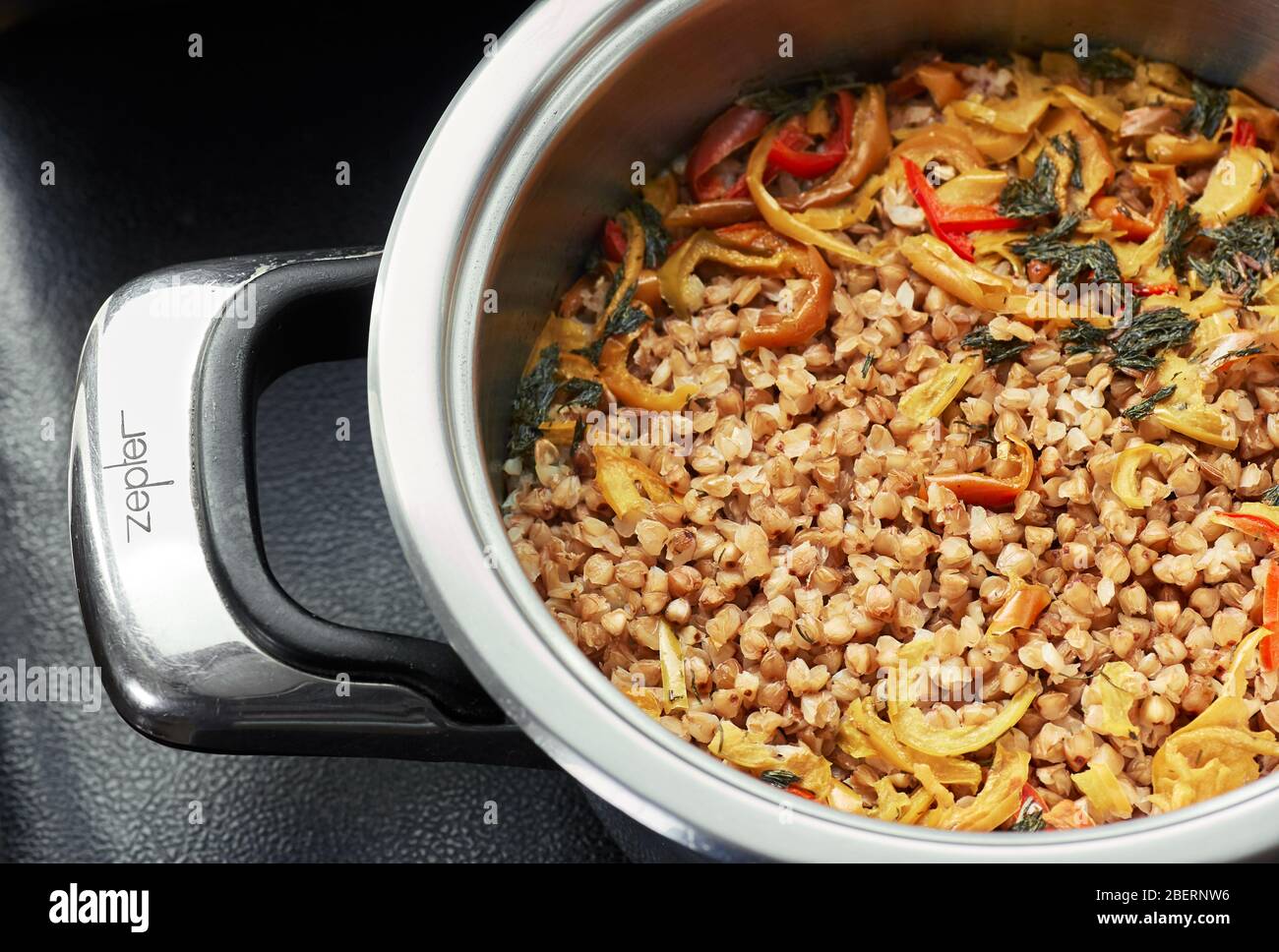 Grano saraceno bollito guarnito con pepe dolce e erbe di aneto in acciaio zepter piccola regina padella, closeup, copia spazio, testurizzato sfondo, vegan sano f Foto Stock