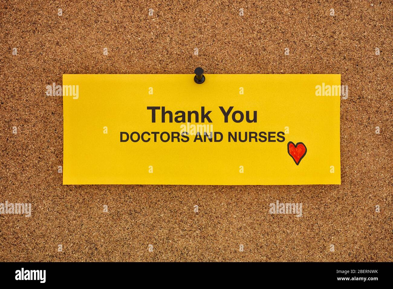 Grazie medici e infermieri scritti su un pezzo di carta giallo che si trova su un bacheca. Concetto di coronavirus. Primo piano. Foto Stock