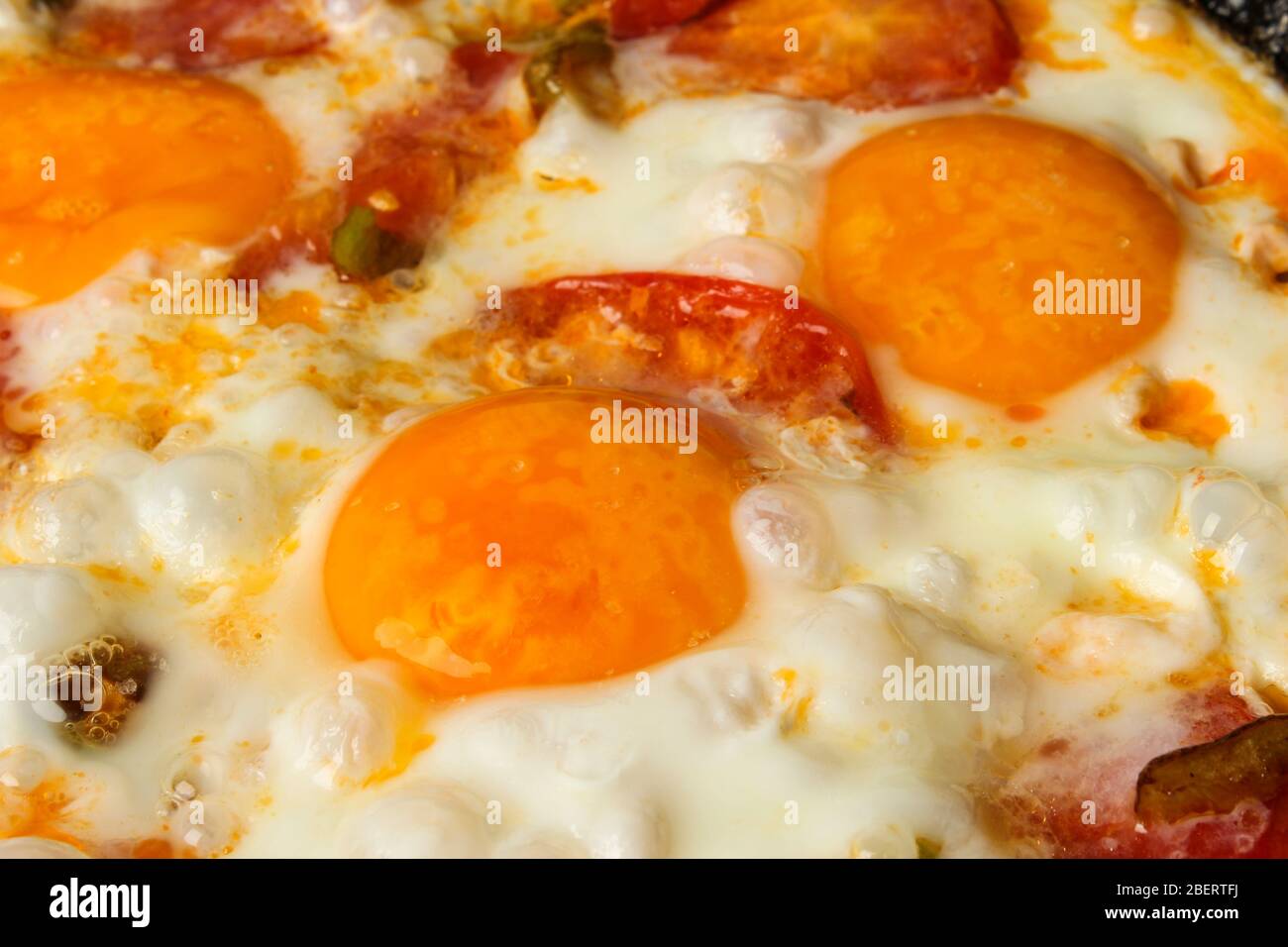 Uova fritte con pomodori in un primo piano in padella come sfondo Foto Stock