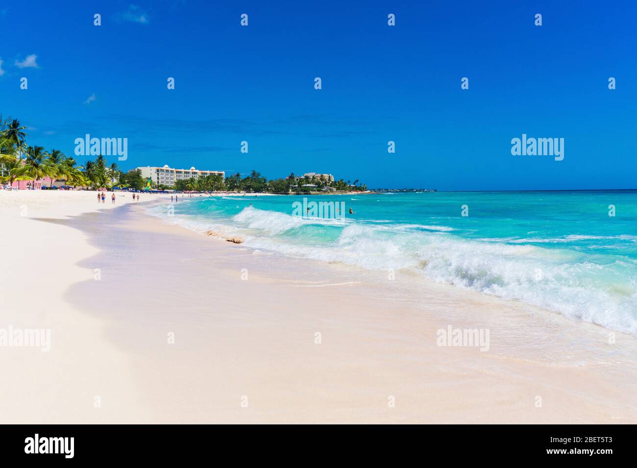 Le persone che camminano e si rilassano mentre le onde rotolano sulla spiaggia di sabbia di dover in una calda giornata di sole Foto Stock