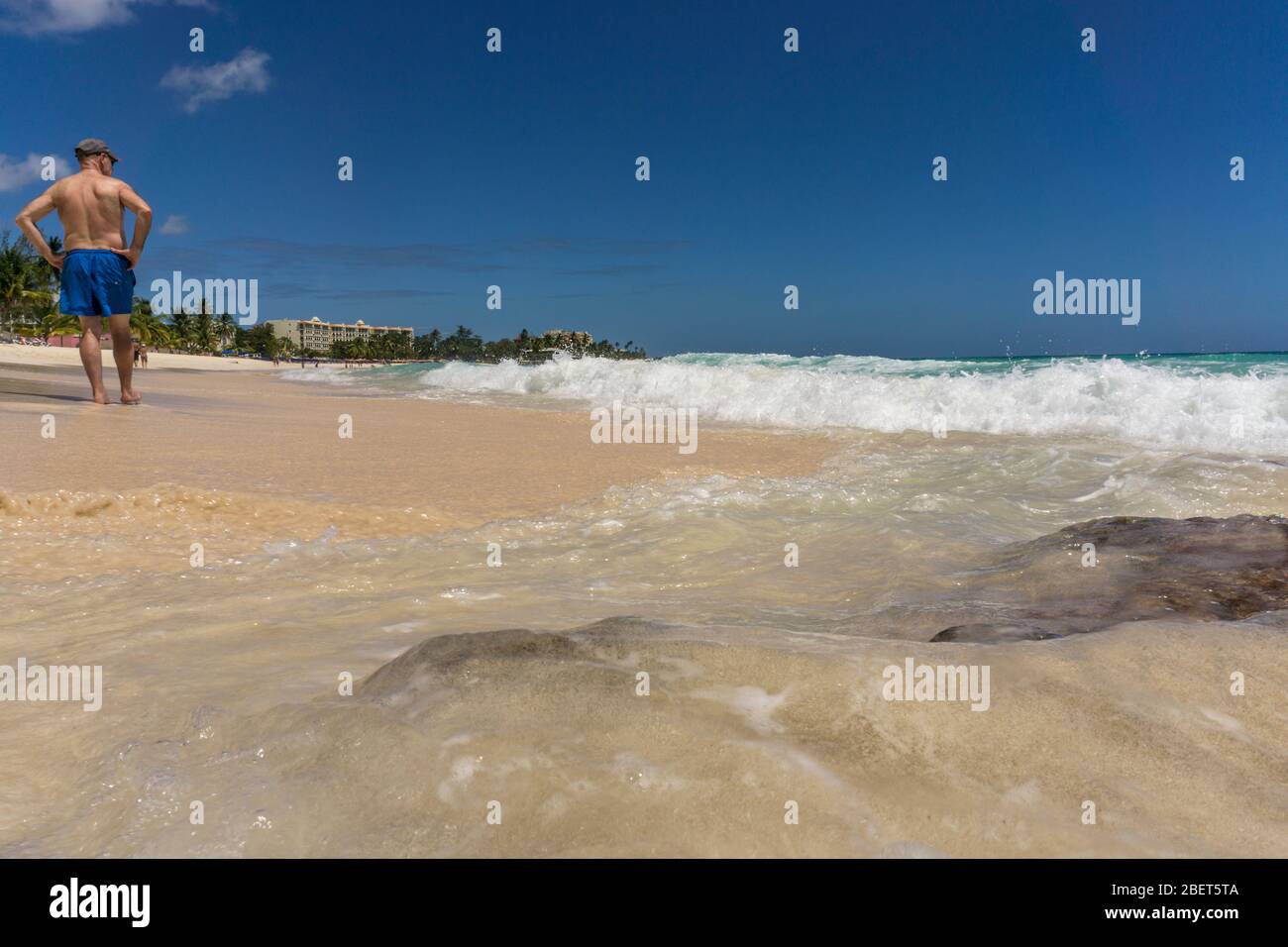 Uomo in piedi sulla spiaggia affacciata sul mare Foto Stock