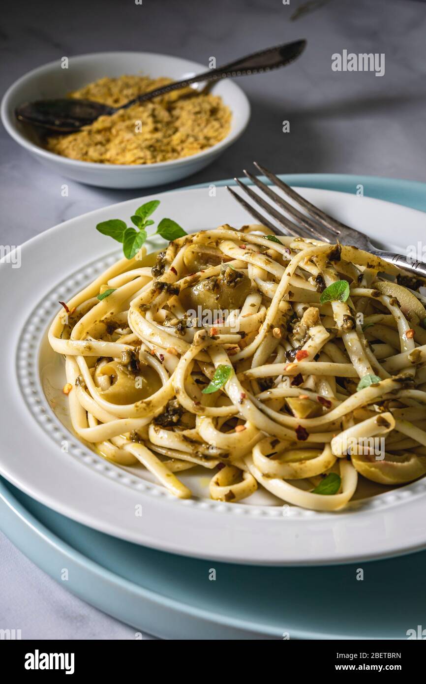 Piatto di pasta vegana. Fettuccine al pesto, olive verdi timo fresco e lievito nutritivo. Foto Stock