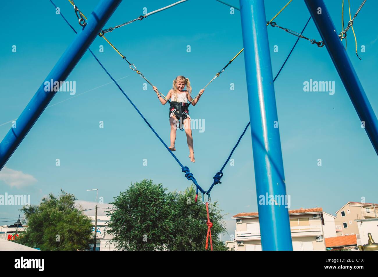 piccolo bambino che si diverte nell'attrazione di salto che vola in alto nel cielo blu Foto Stock