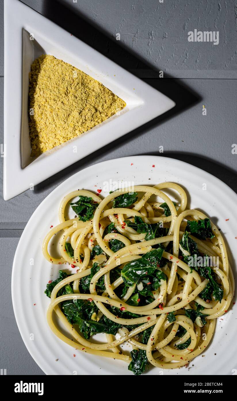Piatto di pasta vegana. Bucatini salza e aglio saltati con lievito nutritivo. Foto Stock