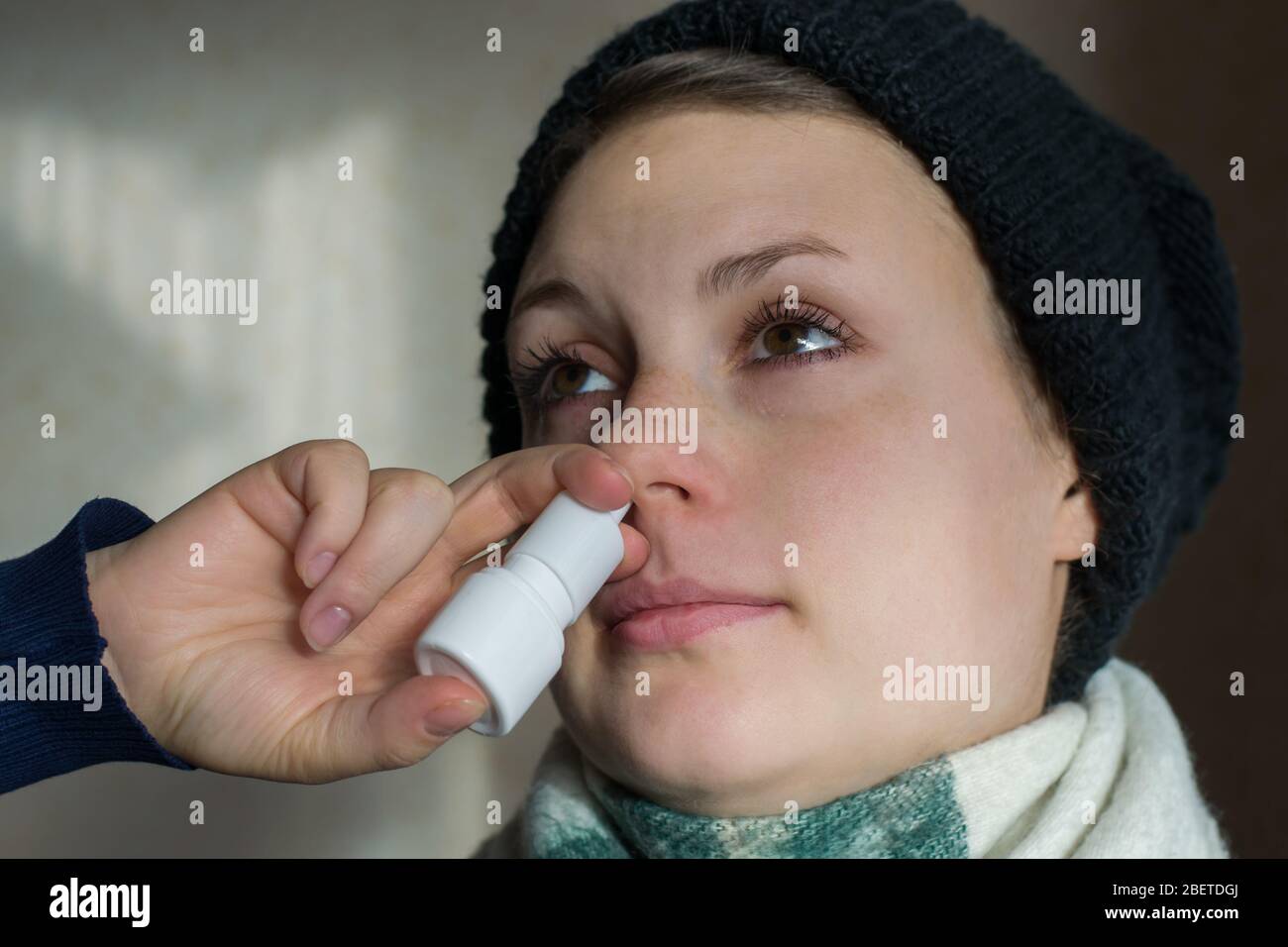 La ragazza spruzza lo spray dal naso che cola nel passaggio nasale Foto Stock