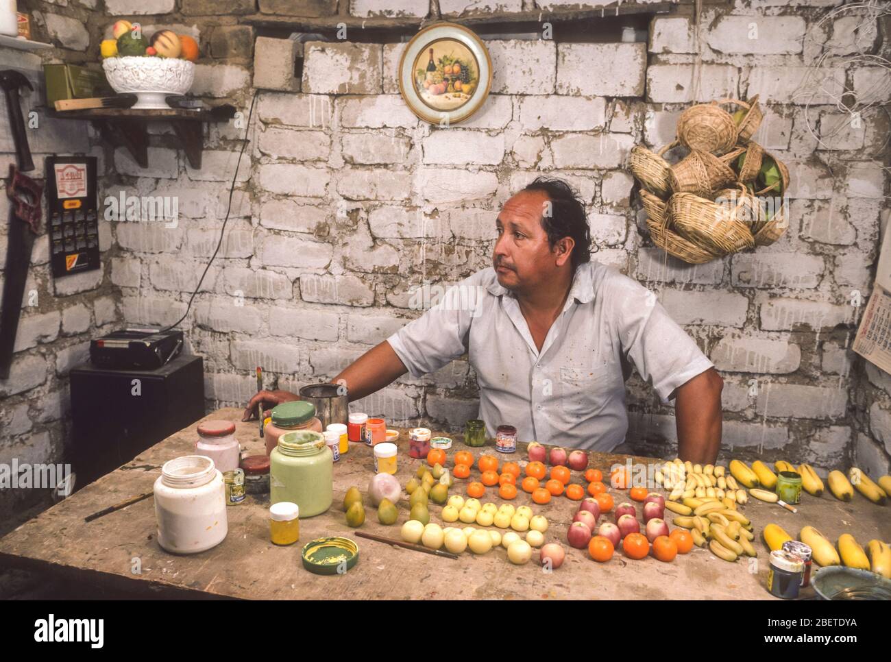 LIMA, PERÙ - l'uomo lavora in casa laboratorio pittura frutta artificiale, in città shanty. Foto Stock