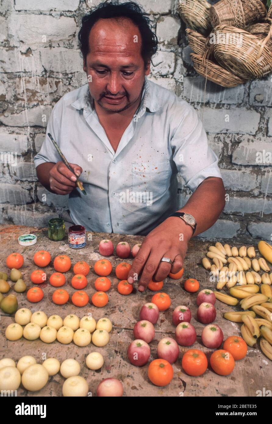 LIMA, PERÙ - l'uomo lavora in casa laboratorio pittura frutta artificiale, in città shanty. Foto Stock
