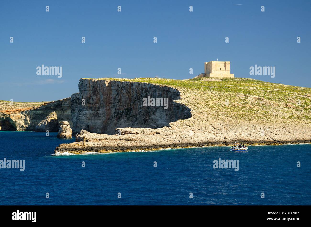 Torre di Santa Maria torre di avvistamento based sull'isola di Comino o Kemmuna dell'arcipelago maltese nel Mar Mediterraneo e barca, Malta Foto Stock
