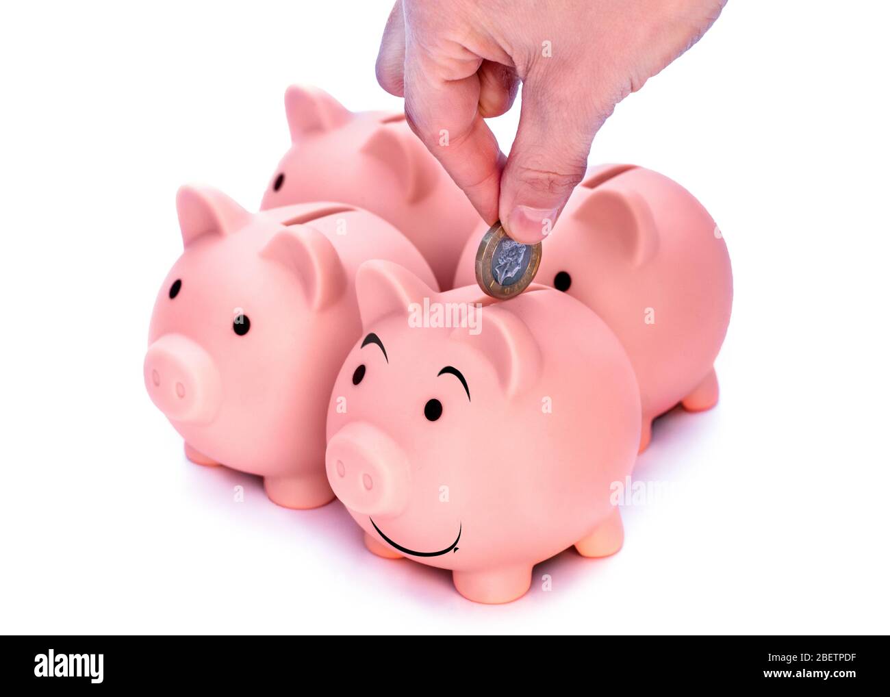 Mano che mette le monete a banca sorridente di piggi. Quattro pigy banchi rosa isolato su sfondo bianco Foto Stock