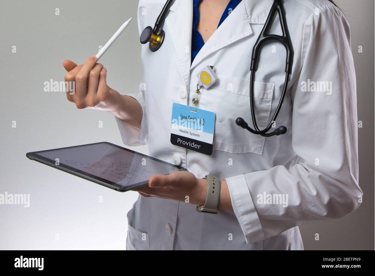 Un medico di professione di donna che fa nota sul tablet per la registrazione dei dati paziente. Ritratto isolato su sfondo grigio Foto Stock